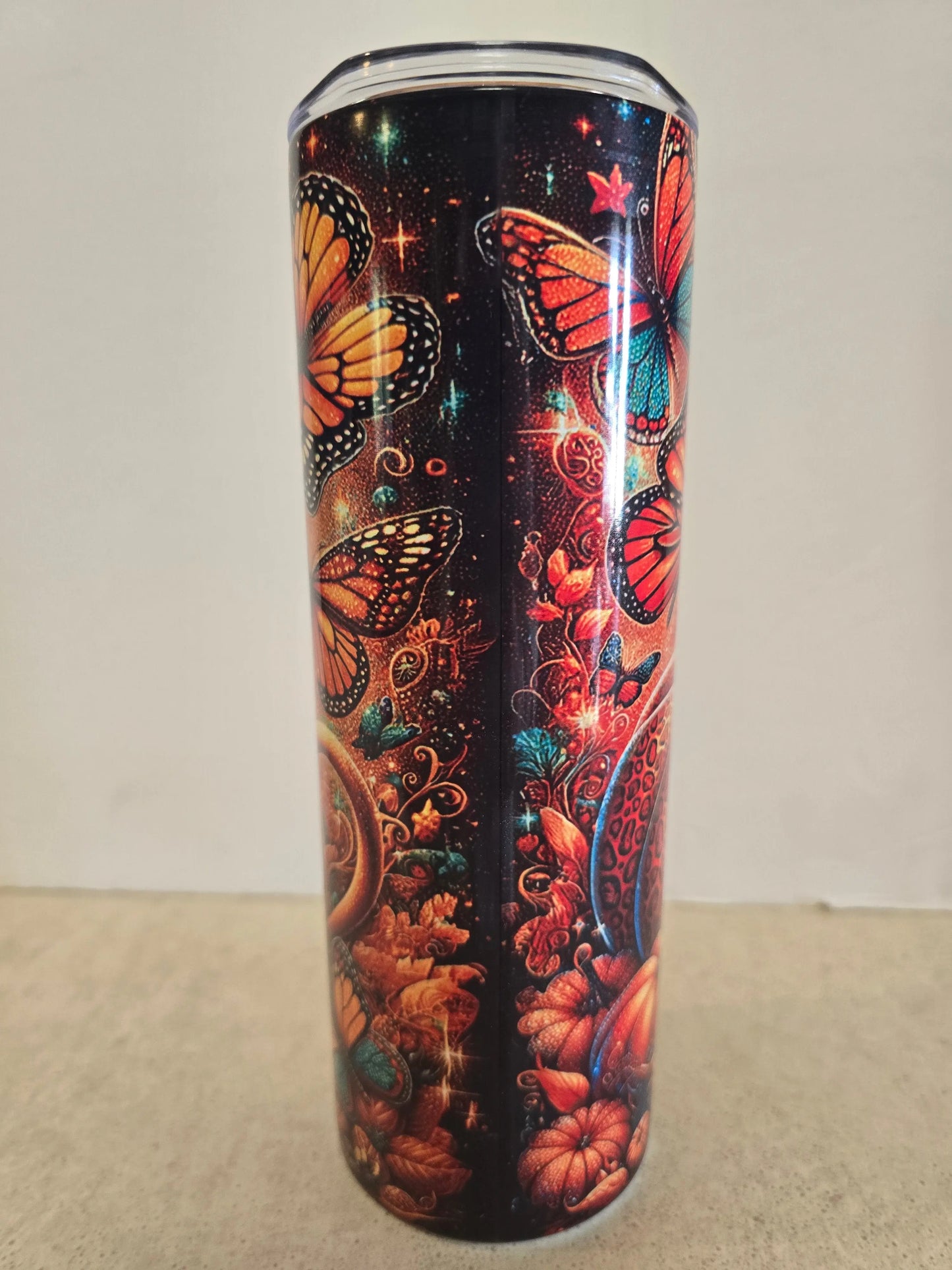 Tumbler with butterfly and floral design on a plain background