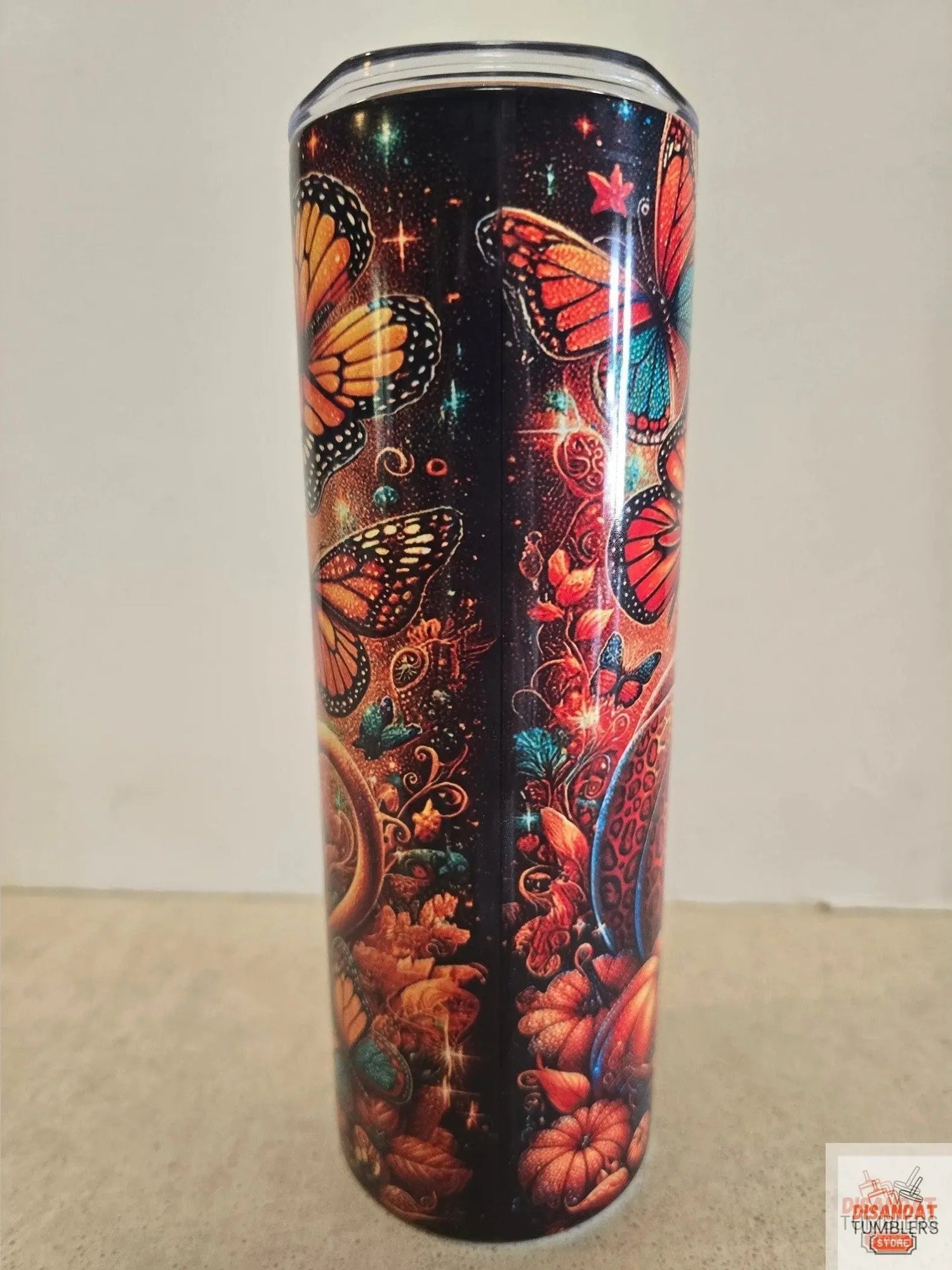 Tumbler with butterfly and floral design on a plain background